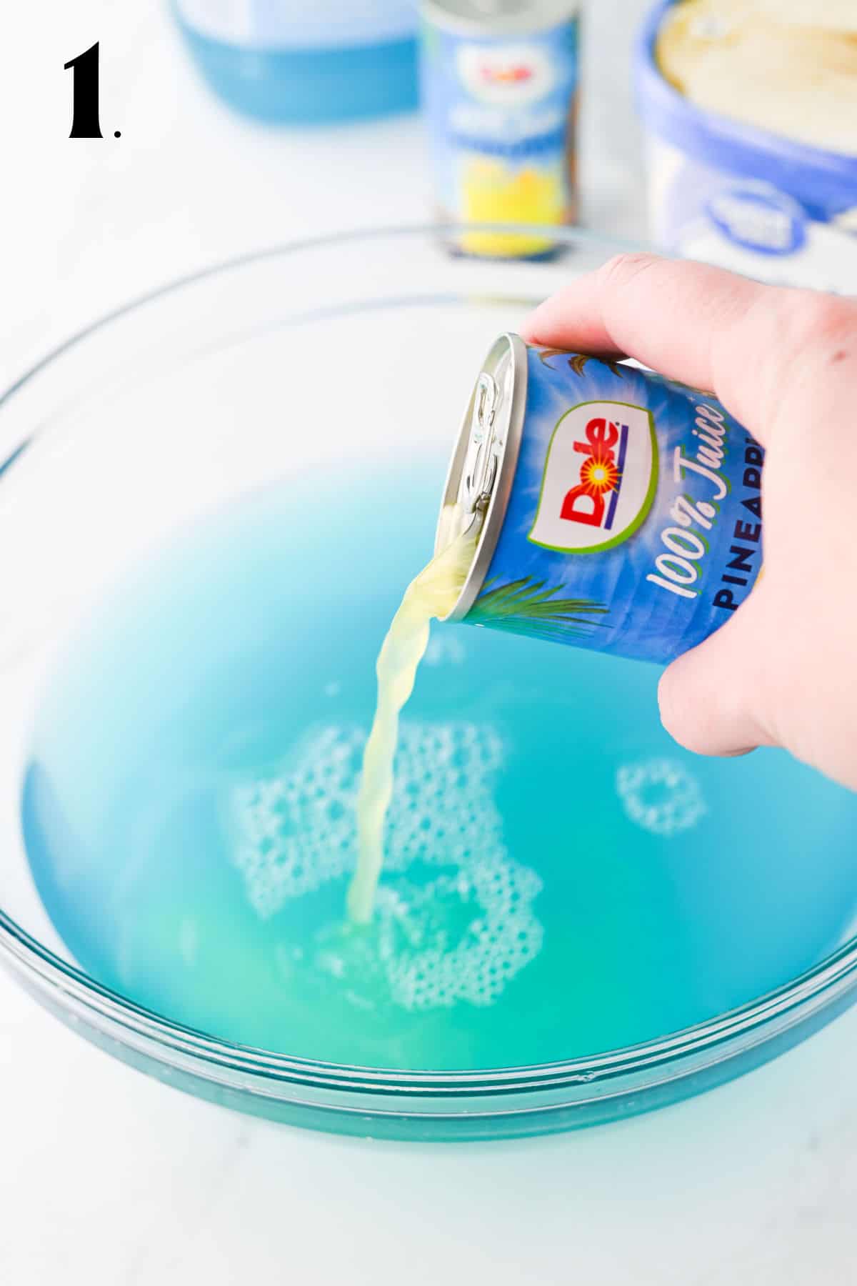 How to Make Blue Punch Step 1 - adding Hawaiian punch and pineapple juice to punch bowl.