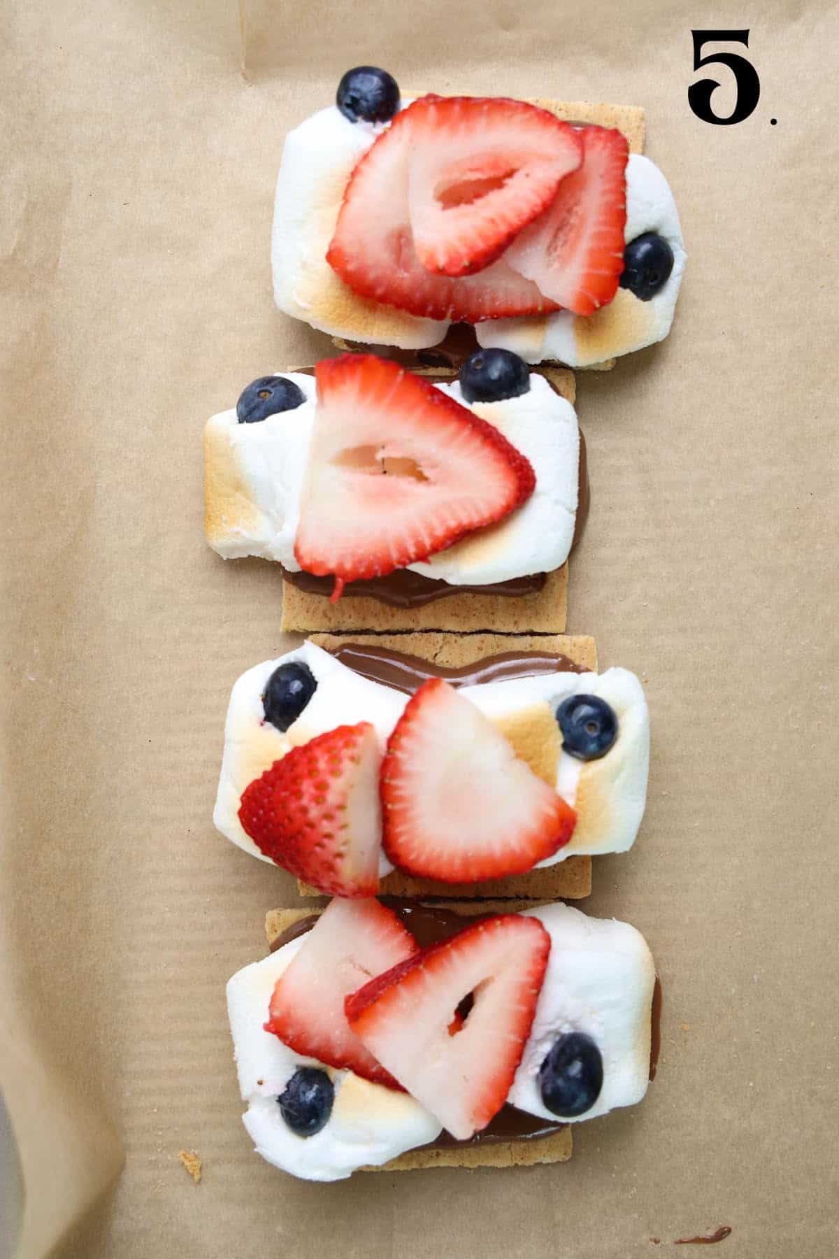 How to Make 4th of July S'mores Step 5 - strawberry slice and blueberries on melted marshmallows.